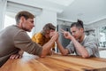 Father competing in arm wrestling with teen son, family spending time together.