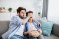 Father covering his son& x27;s eyes from inappropriate content while watching movie on tv with popcorn