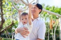 Father and Cute little Asian 2 year old toddler baby boy child having fun exercising outdoor and dad help catch up on Monkey Bars