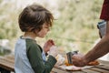 Father dad pours hot coffee tea from thermos into the mug on a family picnic in the mountains. Child school boy kid is Royalty Free Stock Photo