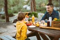 Father dad and school kid boy child having a picnic in the forest camping site with vegetables, juice, coffee, and Royalty Free Stock Photo