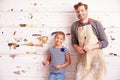 Father And Daughter Against Paint Covered Wall In Art Studio
