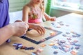 Father and daughter assemble the puzzle while sitting at the table. Games during rain and bad weather, quarantine. Family relaxing Royalty Free Stock Photo