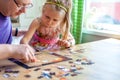 Father and daughter assemble the puzzle while sitting at the table. Games during rain and bad weather, quarantine. Family relaxing Royalty Free Stock Photo