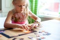 Father and daughter assemble the puzzle while sitting at the table. Games during rain and bad weather, quarantine. Family relaxing Royalty Free Stock Photo