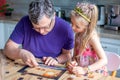 Father and daughter assemble the puzzle while sitting at the table. Games during rain and bad weather, quarantine. Family relaxing Royalty Free Stock Photo