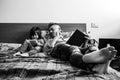 Father and daughter in casual denim clothes are sitting on bed together. The girl having fun writing or drawing while the father Royalty Free Stock Photo