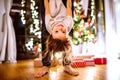 Father with daughter at Christmas tree holding her upside down. Royalty Free Stock Photo