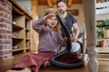 Father and daughter cleaning house, vacuuming the floors with a vacuum cleaner. Young girl helping with house chores.