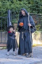 A father and daughter in costume outfits, a Halloween party, a monk and a witch with a Halloween pumpkin in hand.