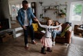 Father and daughter dance happily together while mother sits comfortably on living room sofa