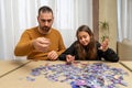 Father and daughter dejected by the difficulty of assembling a puzzle in their living room Royalty Free Stock Photo