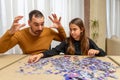 Father and daughter dejected by the difficulty of assembling a puzzle in their living room Royalty Free Stock Photo