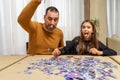 Father and daughter dejected by the difficulty of assembling a puzzle in their living room Royalty Free Stock Photo