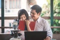 Father and daughter doing learning activities outside the classroom on science discovery using a microscope and computer at home