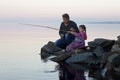 Father and daughter fishing on lake at sunset