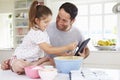 Father And Daughter Following Cake Recipe On Digital tablet