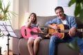 Father daughter with guitars looking to the camera at home Royalty Free Stock Photo