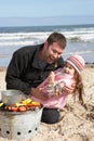 Father And Daughter Having Barbeque On Beach