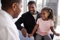 Father And Daughter Having Consultation With Female Pediatrician In Hospital Office