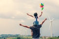 Father and daughter having fun to play together. Asian child girl playing with wind turbine and riding on father`s shoulders Royalty Free Stock Photo