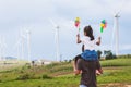 Father and daughter having fun to play together. Asian child girl playing with wind turbine and riding on father`s shoulders Royalty Free Stock Photo