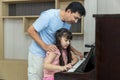 Father and daughter at home playing music on a piano. Dad and daughter are playing the piano. Pianist teacher teaching girl kid st Royalty Free Stock Photo