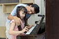 Father and daughter at home playing music on a piano. Dad and daughter are playing the piano. Pianist teacher teaching girl kid st Royalty Free Stock Photo