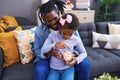 Father and daughter inserting coin on piggy bank sitting on sofa at home Royalty Free Stock Photo