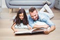 Father and daughter looking in picture book on floor Royalty Free Stock Photo