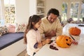 Father And Daughter Making Halloween Decorations At Home