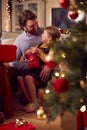 Father And Daughter Opening Gifts Around Christmas Tree At Home Royalty Free Stock Photo