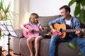 Father daughter playing guitar looking at each other with complicity