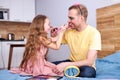 father and daughter playing at home with make up brush, doing make-up Royalty Free Stock Photo