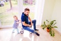 Father and daughter playing together, riding a bike indoors Royalty Free Stock Photo