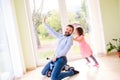 Father and daughter playing together, riding a bike indoors Royalty Free Stock Photo