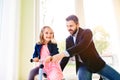 Father and daughter playing together, riding a bike indoors Royalty Free Stock Photo