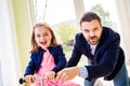 Father and daughter playing together, riding a bike indoors Royalty Free Stock Photo