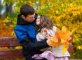 Father and daughter portrait in an autumn park. Happy people pose against the background of beautiful yellow trees. They sit on a Royalty Free Stock Photo