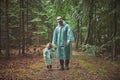 Father and daughter in raincoats walk in the evening forest Royalty Free Stock Photo