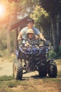 Father and daughter riding on quad atv on dirt field