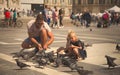 Father and daughter in a shared moment they play with the pigeons in Piazza Duomo in Milan