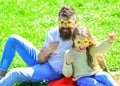 Father and daughter sits on grass at grassplot, green background. Superstar concept. Child and dad posing with star