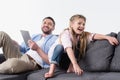 Father with daughter sitting on sofa with digital tablet