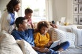 Father and daughter sitting on sofa using tablet computer, mother and toddler son leaning behind them, low angle Royalty Free Stock Photo