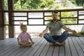 Father and daughter sitting on wooden floor, meditating with close eyes Royalty Free Stock Photo