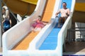 Father and daughter slide down hill on air mattress in water park Royalty Free Stock Photo