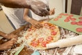 Father and daughter sprinkling some cheese over pizza with salami