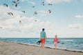 Father and daughter standing on sea ocean beach and watching seagulls in  sky. Dad and child girl travelling spending time Royalty Free Stock Photo