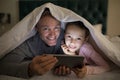 Father and daughter using digital tablet under blanket on bed Royalty Free Stock Photo